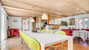 A spacious dining area with a white table and yellow chairs, wooden ceiling beams, and a red sofa in the background. - Lovely holiday home with wilderness bath and outdoor sauna, centrally located. (Thisted)