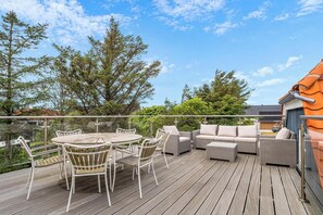 A wooden deck with outdoor furniture, including a round table and chairs, and a sofa set. - Lovely holiday home with wilderness bath and outdoor sauna, centrally located. (Thisted)