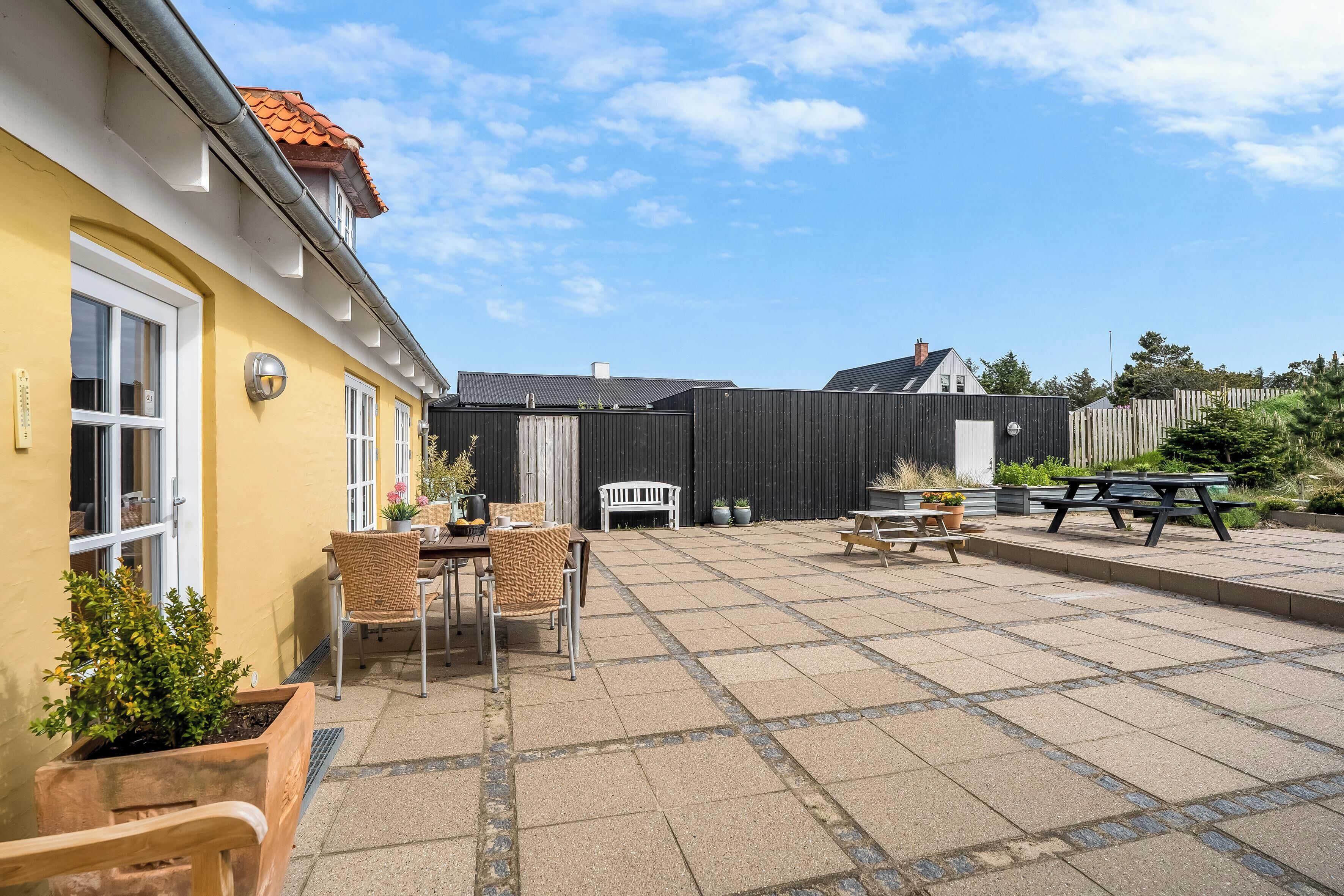Une cour avec une table de patio, des chaises et un banc.