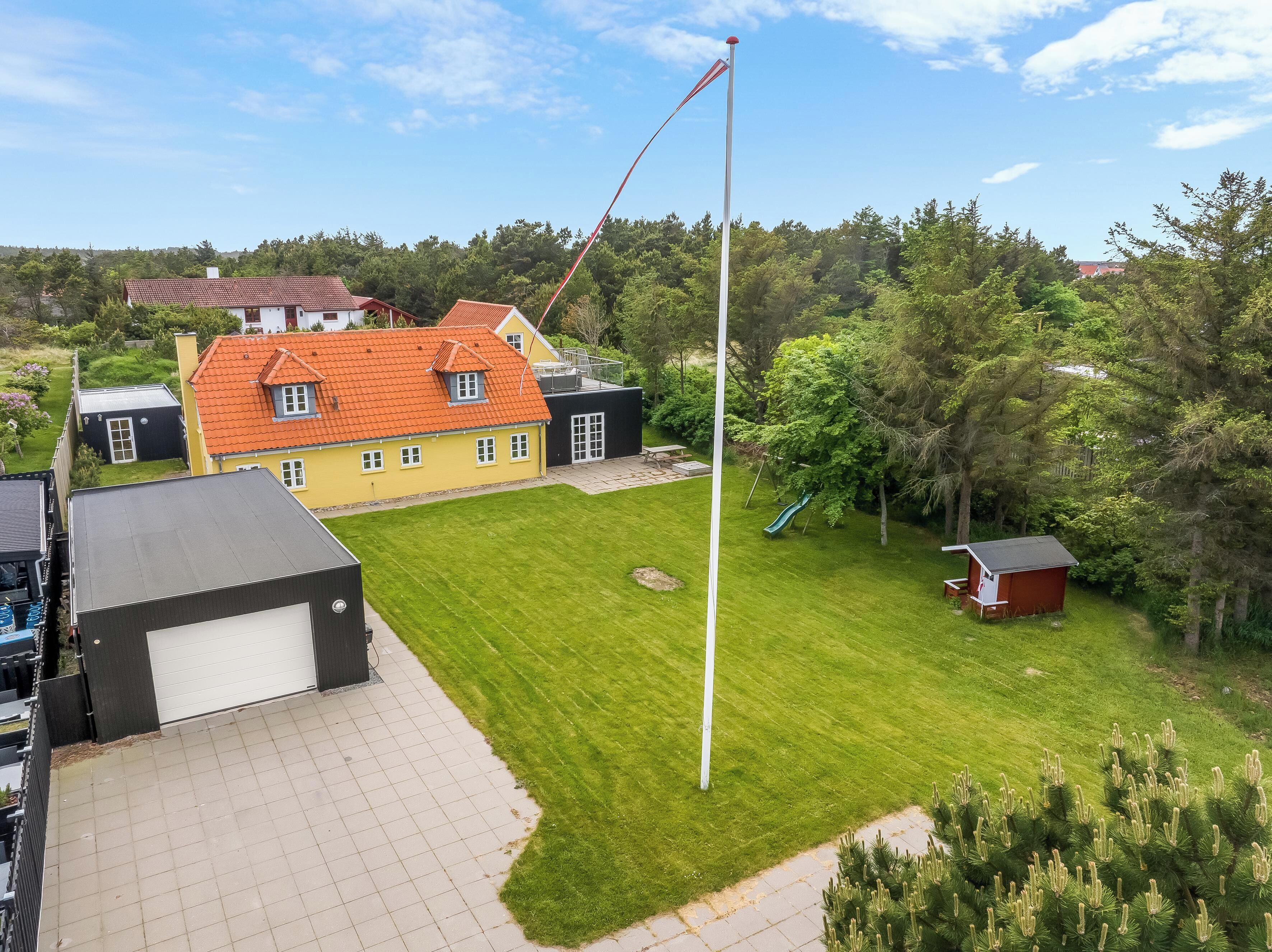 A residential area with a house, a flagpole, a green lawn, and a small shed.