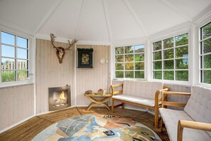 Ein Zimmer mit Kamin, Holzmöbeln, einem Teppich und einem Hirschschädel an der Wand.