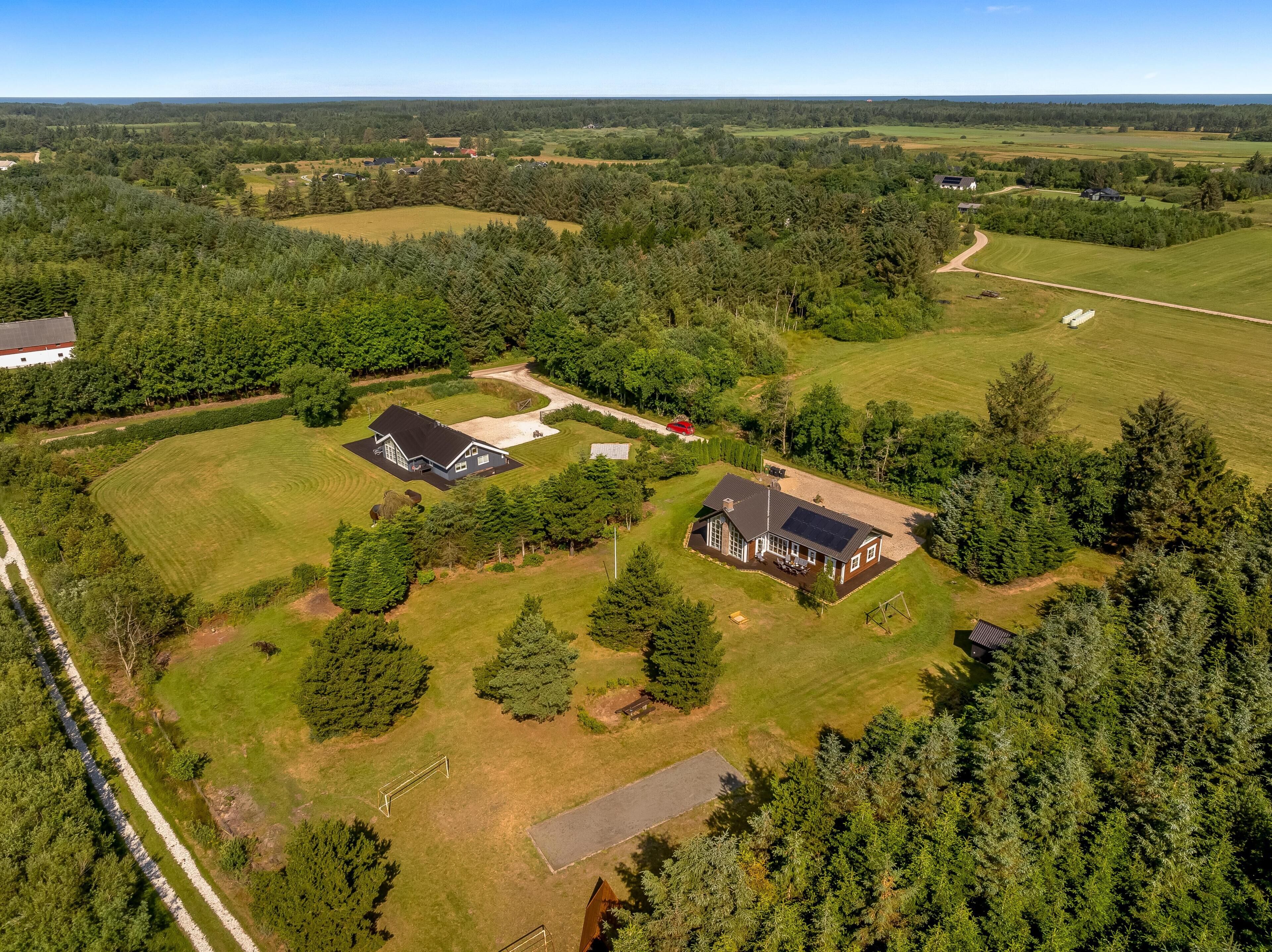 A large property with multiple buildings, expansive grassy fields, and dense forested areas.