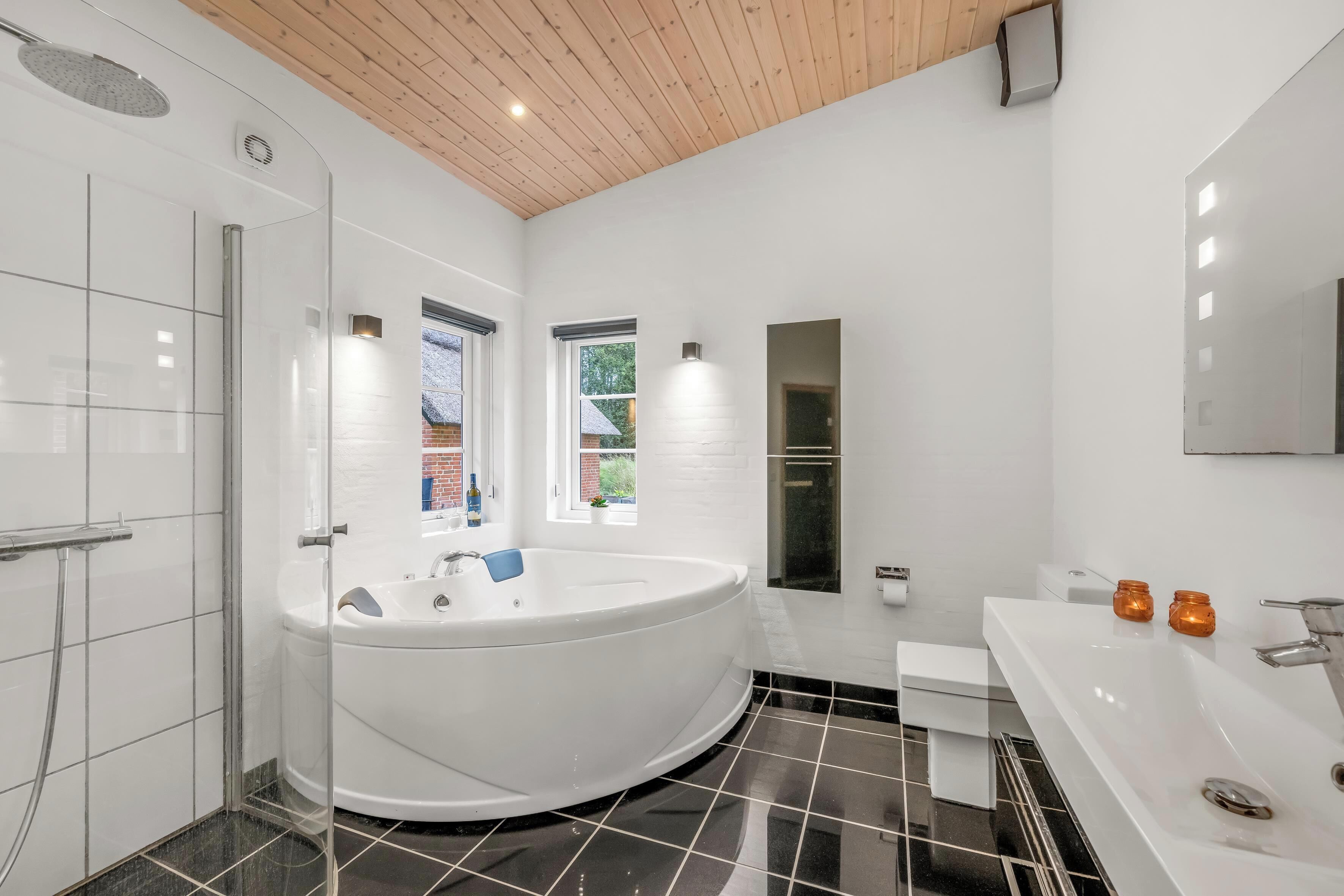 Une salle de bain moderne dotée d’une grande baignoire, d’une douche séparée et d’un meuble-lavabo avec un miroir.