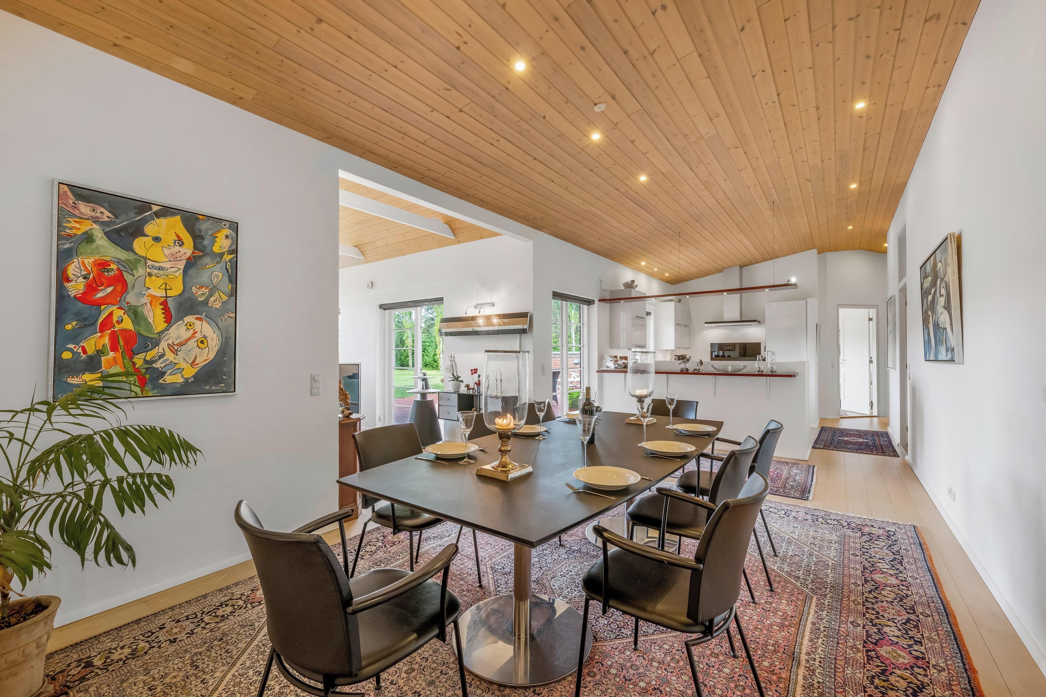 Un espace repas avec une longue table, des chaises et une plante en pot.