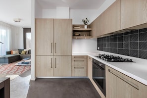 Eine moderne Küche mit Holzschränken, einem Gasherd und einer schwarzen Küchenrückwand.