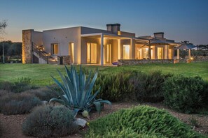 A modern house with a stone facade, large windows, and a well-lit entrance.