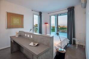 Ein modernes Schlafzimmer mit großem Fenster, einem Nachttisch mit Lampe und Blick ins Freie.