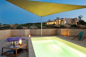 A pool area with a table, candles, and a yellow canopy.