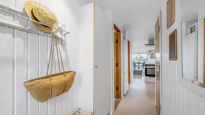 Un couloir orné d’un panier suspendu, d’un chapeau de paille et d’une étagère en bois.