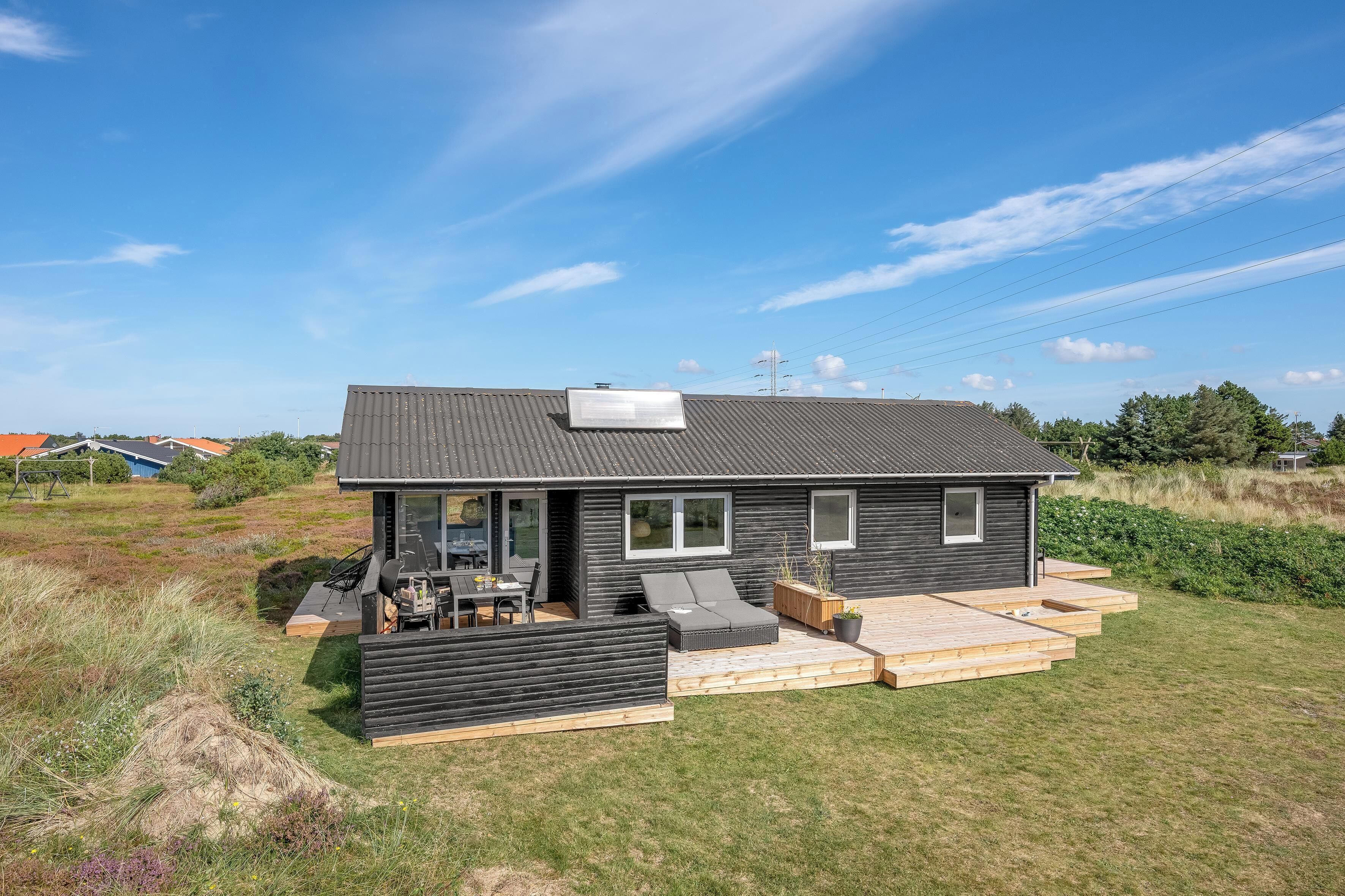 Et moderne hus med en patio, udendørs møbler og udsigt over det omkringliggende landskab.