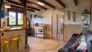 Una cocina con barra, una mesa de comedor con sillas amarillas, un tapete tejido y un sofá con cojines estampados.