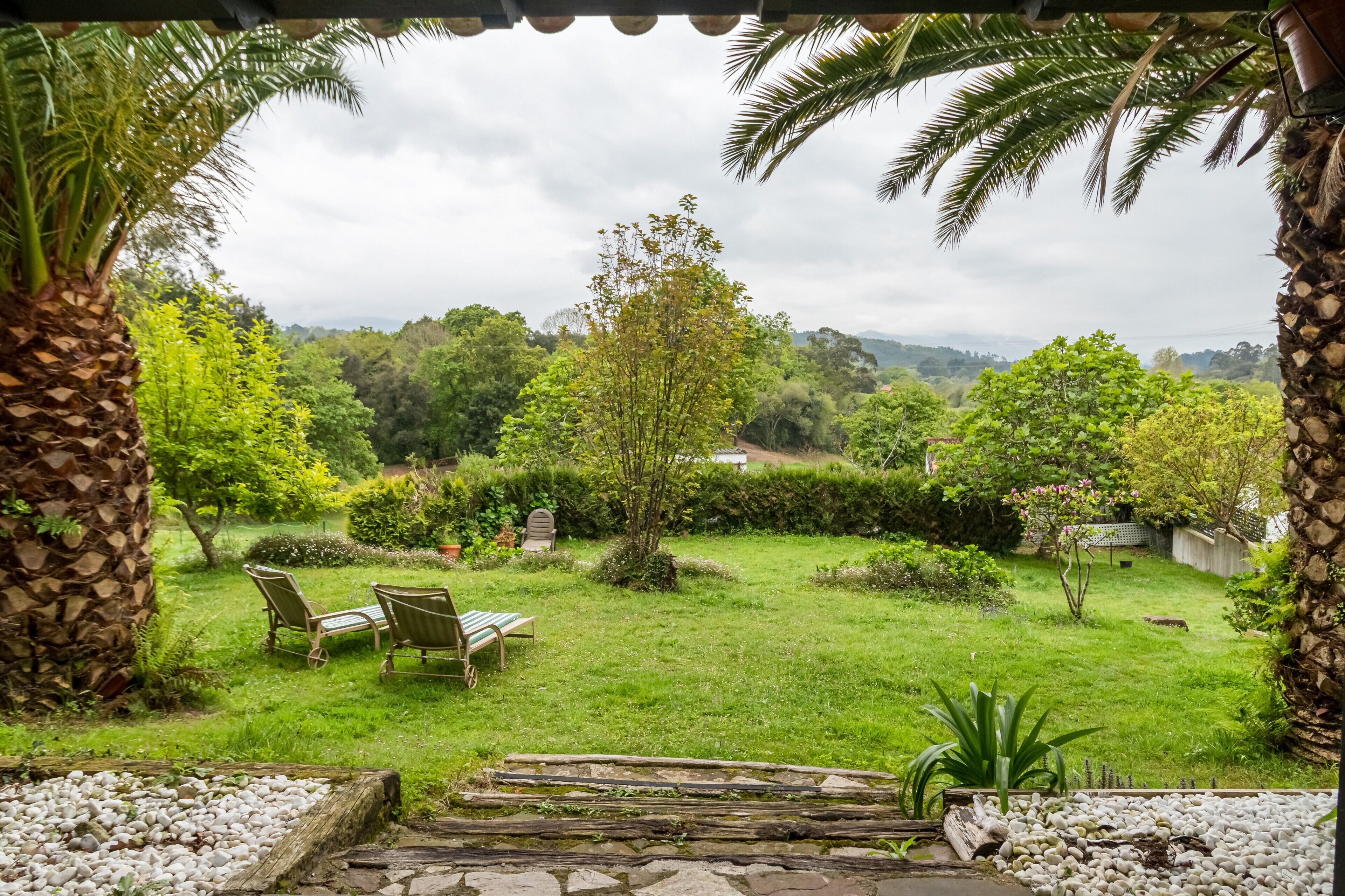 Un jardin avec un sentier en pierre, deux chaises et une vue sur un paysage luxuriant.