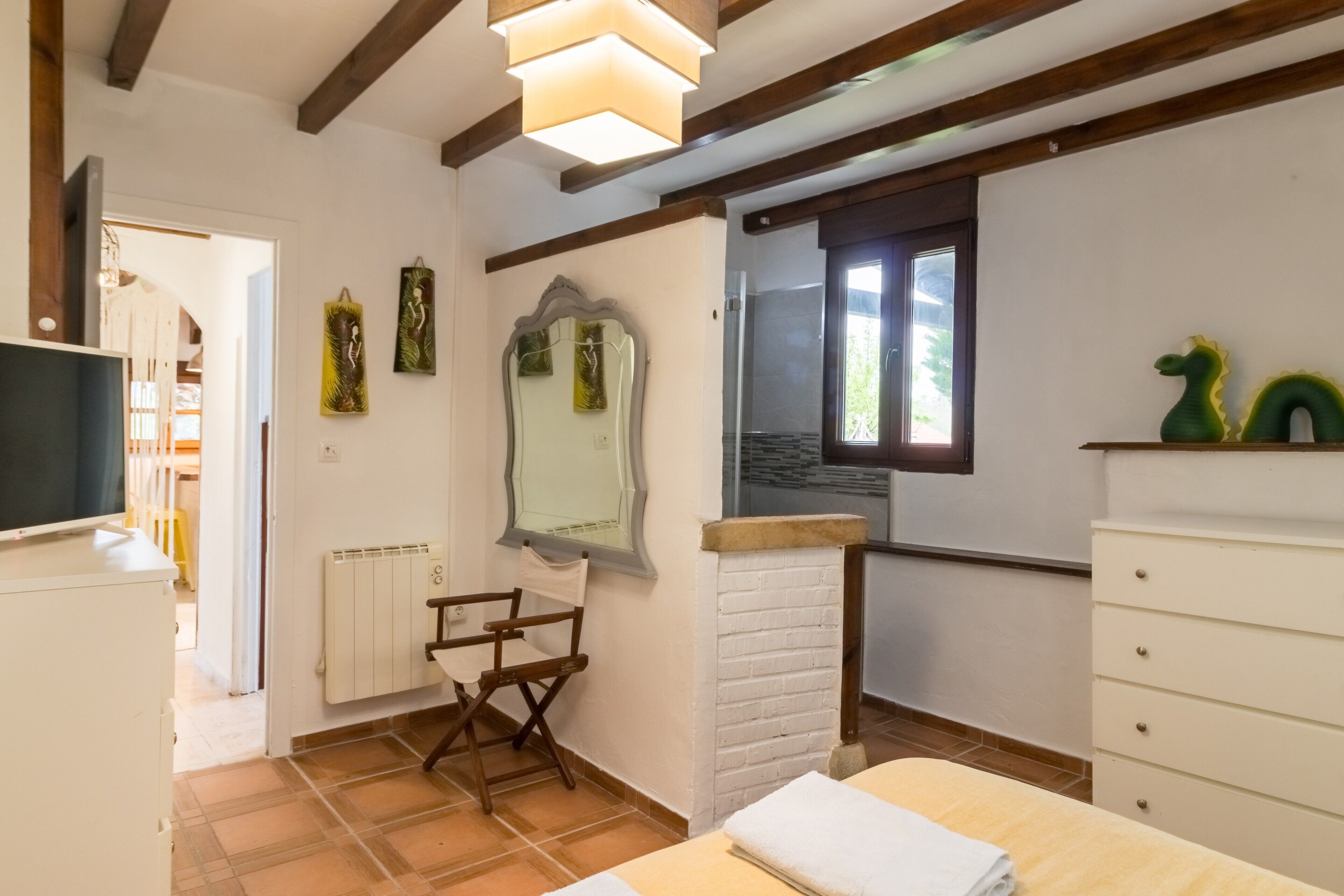 Une chambre à coucher avec un lit, une commode, un miroir et une fenêtre.