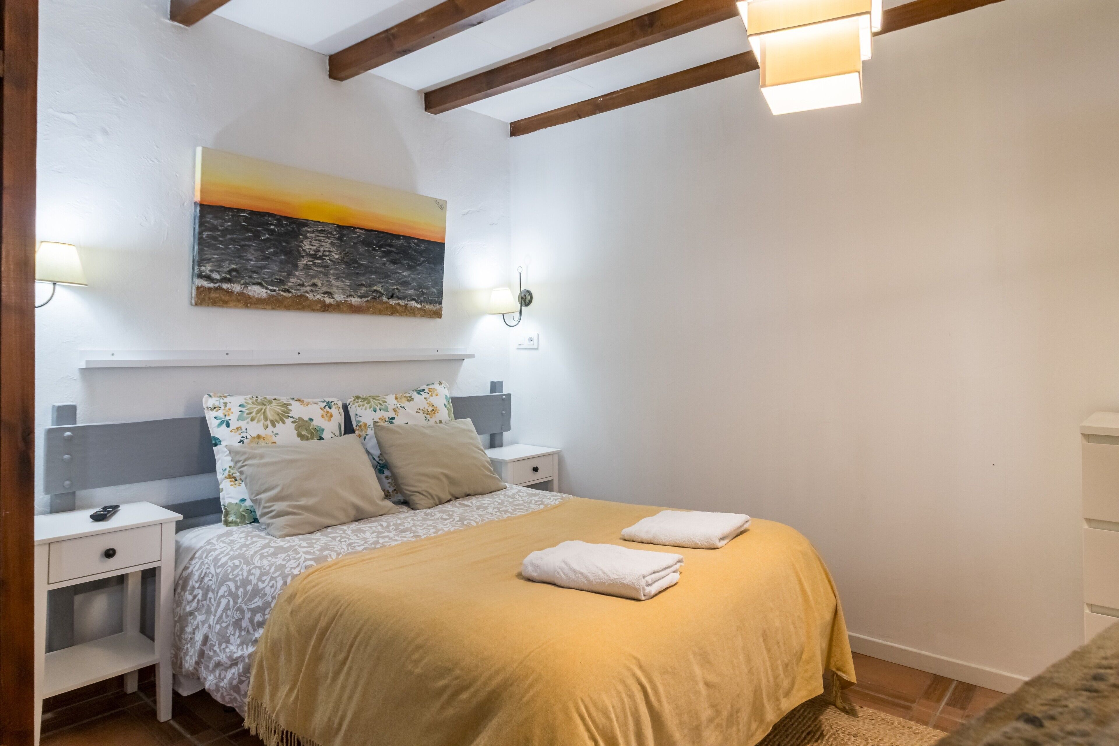Ein Schlafzimmer mit Bett, Nachttischen, einem Gemälde und einer Lampe.