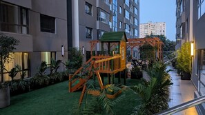 A residential building with a playground, green lawn, and potted plants. - Charming 2-bedroom apartment in cool Nairobi neighborhood (Nairobi)