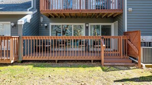 Ein zweistöckiges Gebäude mit einer Holzdiele, einer überdachten Terrasse und einer sichtbaren Heizungs- und Klimaanlage.
