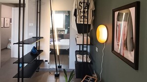 Une chambre moderne avec un lit, un bureau debout, une plante en pot et un tableau encadré au mur.