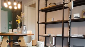 Un espace de vie moderne comprenant une table à manger, une machine à café, une bibliothèque et un ordinateur portable posé sur un bureau.