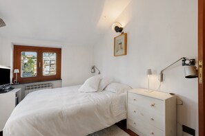 A bedroom with a bed, bedside tables, a dresser, a window with a view, and wall-mounted lighting. - ‘Chiavari Elegante’ Apartment with Private Terrace, Balcony and Air Conditioning (Chiavari)