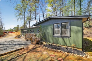 A small, single-story building with a green exterior, a front porch, and a window.