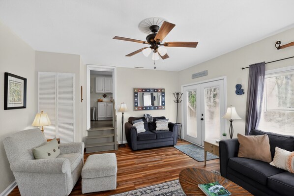 A living room with a ceiling fan, a sofa, a chair, and a coffee table. There is a staircase leading to an upper level.
