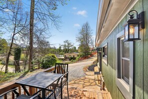 A wooden deck with a table and chairs, a stone pathway, and a view of houses and trees.