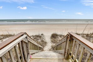 Eine Holzpromenade führt zu einem Strand mit freiem Blick auf den Ozean.