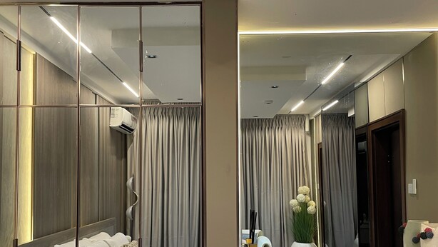 Une chambre à coucher moderne avec un lit, une table de chevet et un grand miroir.