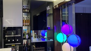 Une cuisine moderne dotée d’appareils électroménagers intégrés, d’un coin bar avec des bouteilles et d’un système d’éclairage original.