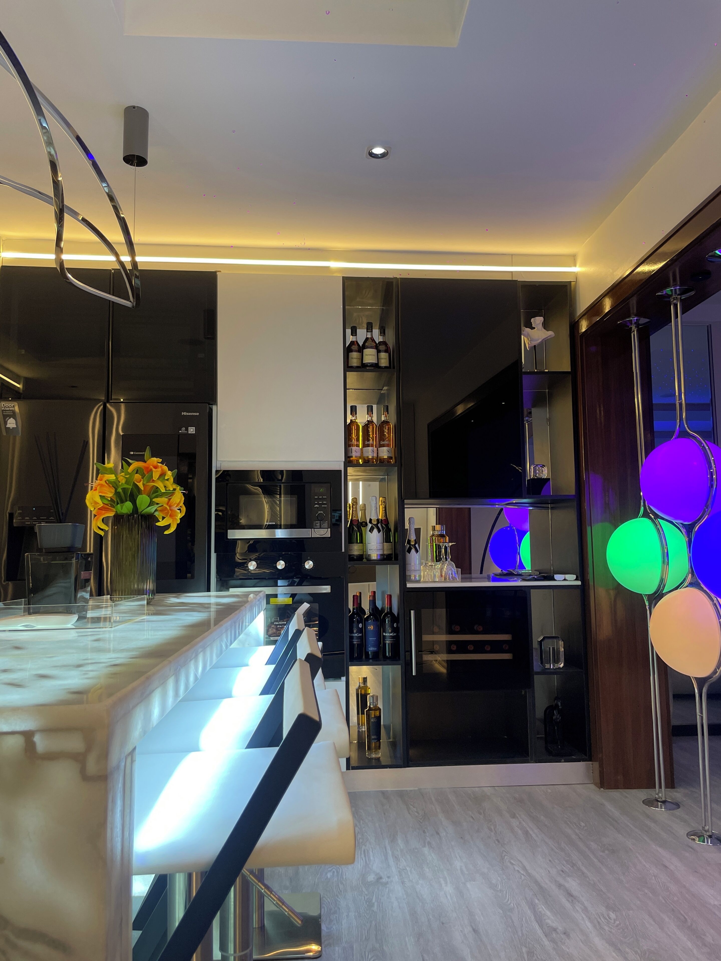 A modern kitchen with a built-in wine fridge, a bar area with stools, and a decorative vase with flowers.
