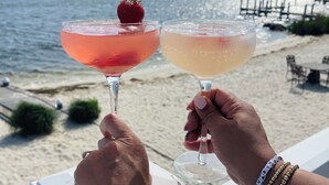 Two people holding cocktail glasses on a balcony with a beach view. - Water front OASIS - Voted #1 Vacation Rental in the Jersey Shore 2024 (Seaside Heights)