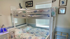 A bunk bed with a starfish and shell pattern, a bedside table with a lamp, and a small desk with a chair. - Water front OASIS - Voted #1 Vacation Rental in the Jersey Shore 2024 (Seaside Heights)