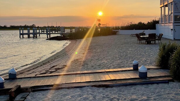 A beach with a wooden deck, a pier, and a building with outdoor seating. - Water front OASIS - Voted #1 Vacation Rental in the Jersey Shore 2024 (Seaside Heights)
