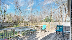 Une terrasse en bois avec une table et des chaises, entourée d’une clôture en bois et d’arbres.