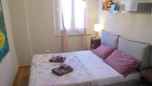 A bed with floral bedding, two pillows, and two folded towels. - Apartment 'Cavour' with Wi-Fi (Genova)