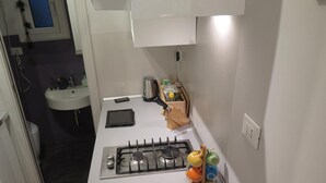 A compact kitchen with a gas stove, a sink, and a small countertop area. - Apartment 'Cavour' with Wi-Fi (Genova)