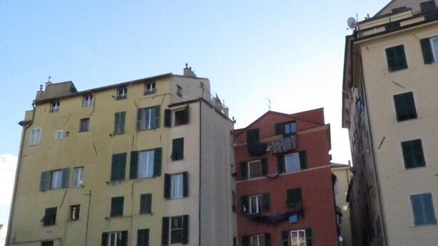 A multi-story building with a ground-level entrance, a visible restaurant sign, and a parked car. - Apartment 'Cavour' with Wi-Fi (Genova)