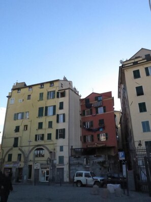 Un edificio a più piani con ingresso a livello strada, un cartello di un ristorante ben visibile e un'auto parcheggiata.
