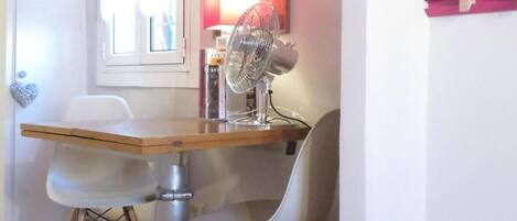 Un comedor con una mesa, sillas, un ventilador y una ventana con cortinas.