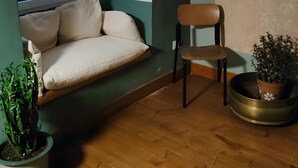 Ein Eckzimmer mit Holzboden, einer Bank, einem Stuhl und zwei Blumentöpfen.