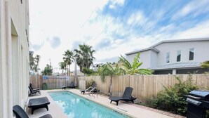 A backyard with a swimming pool, lounge chairs, and a wooden fence. - Beach Access & Poolside Patio! Easter Special! (South Padre Island)