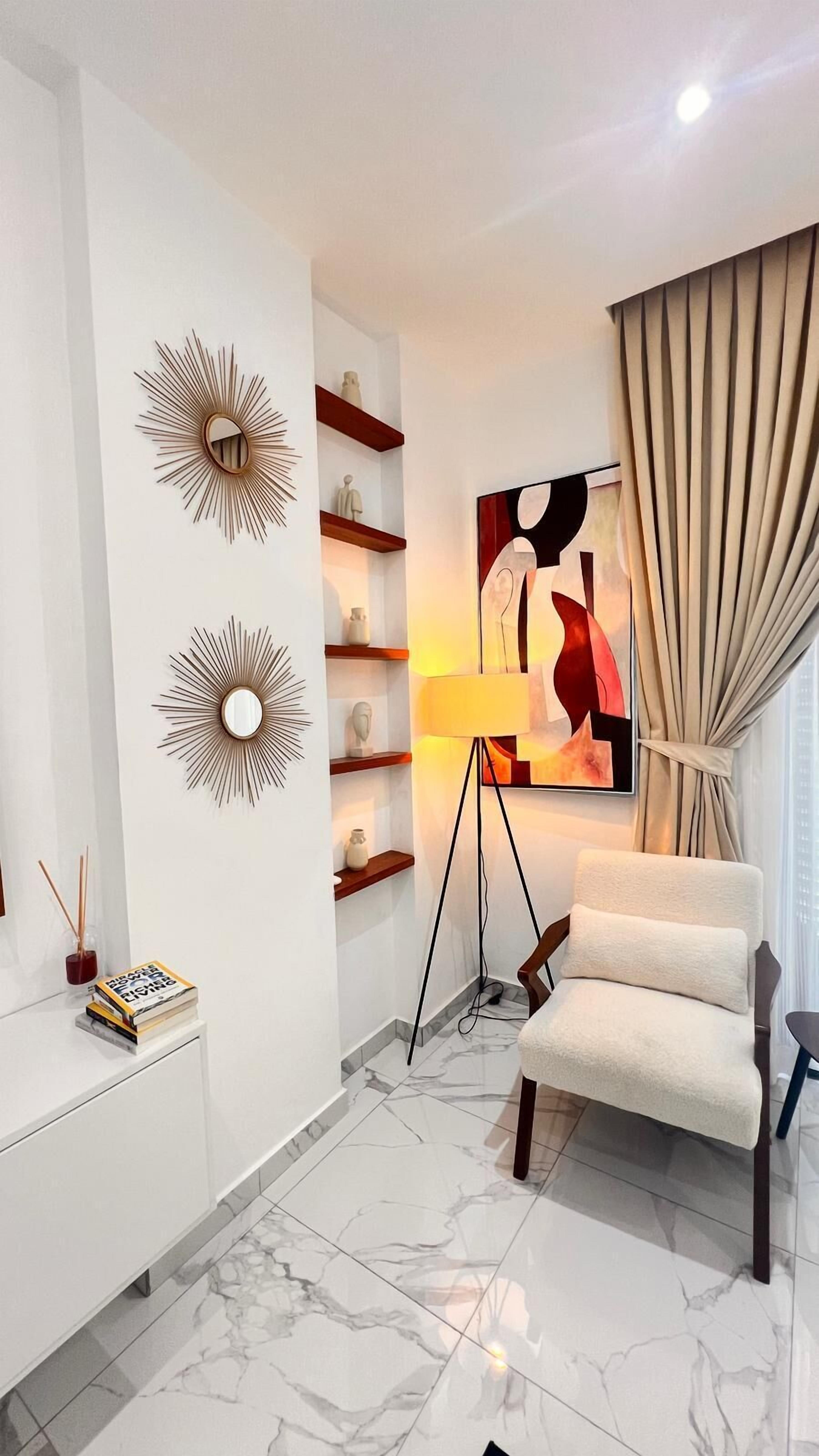 Een moderne woonkamer met een marmeren vloer, een witte bank, een vloerlamp en een schilderij aan de muur.