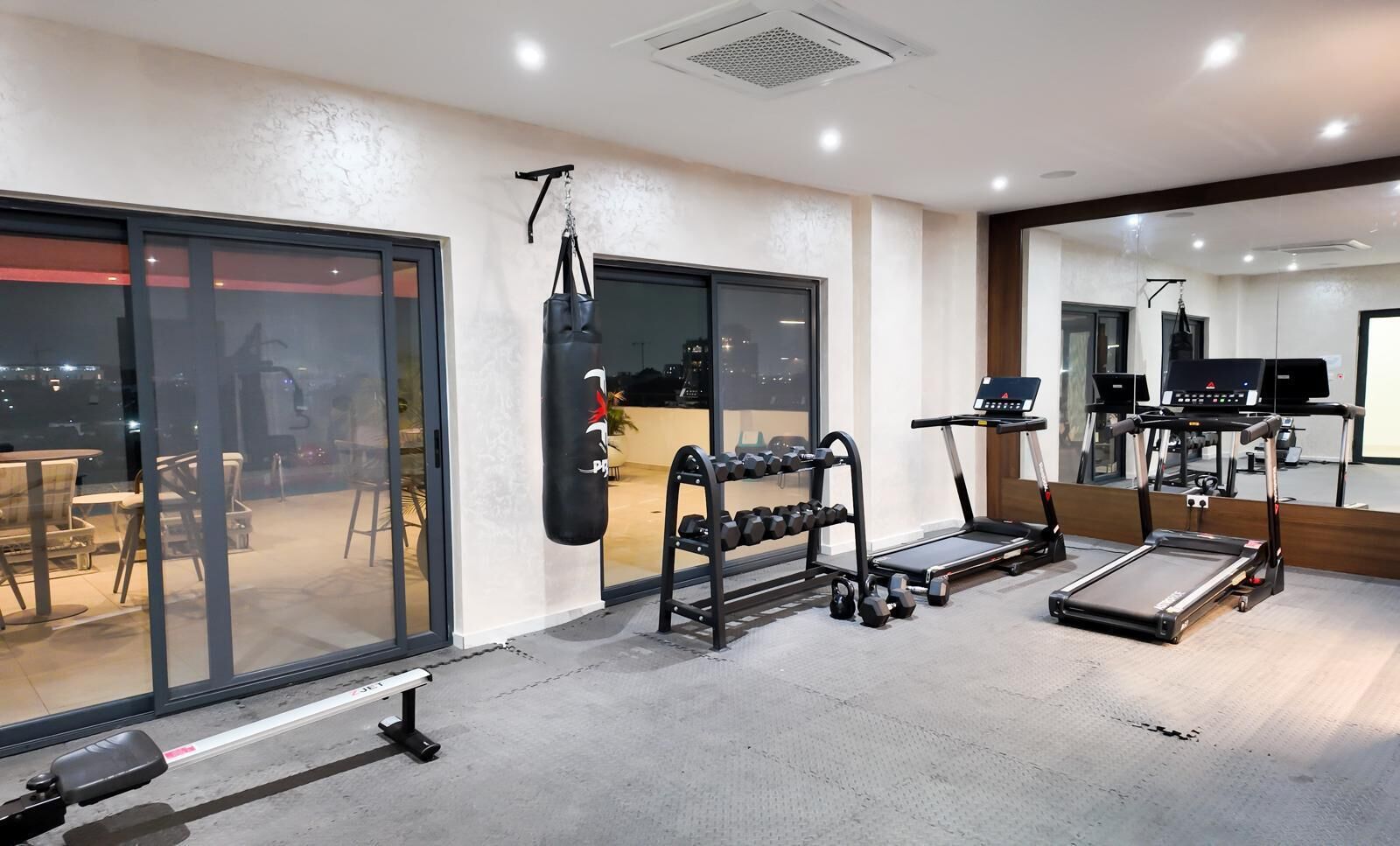 A gym with a treadmill, punching bag, and dumbbells.