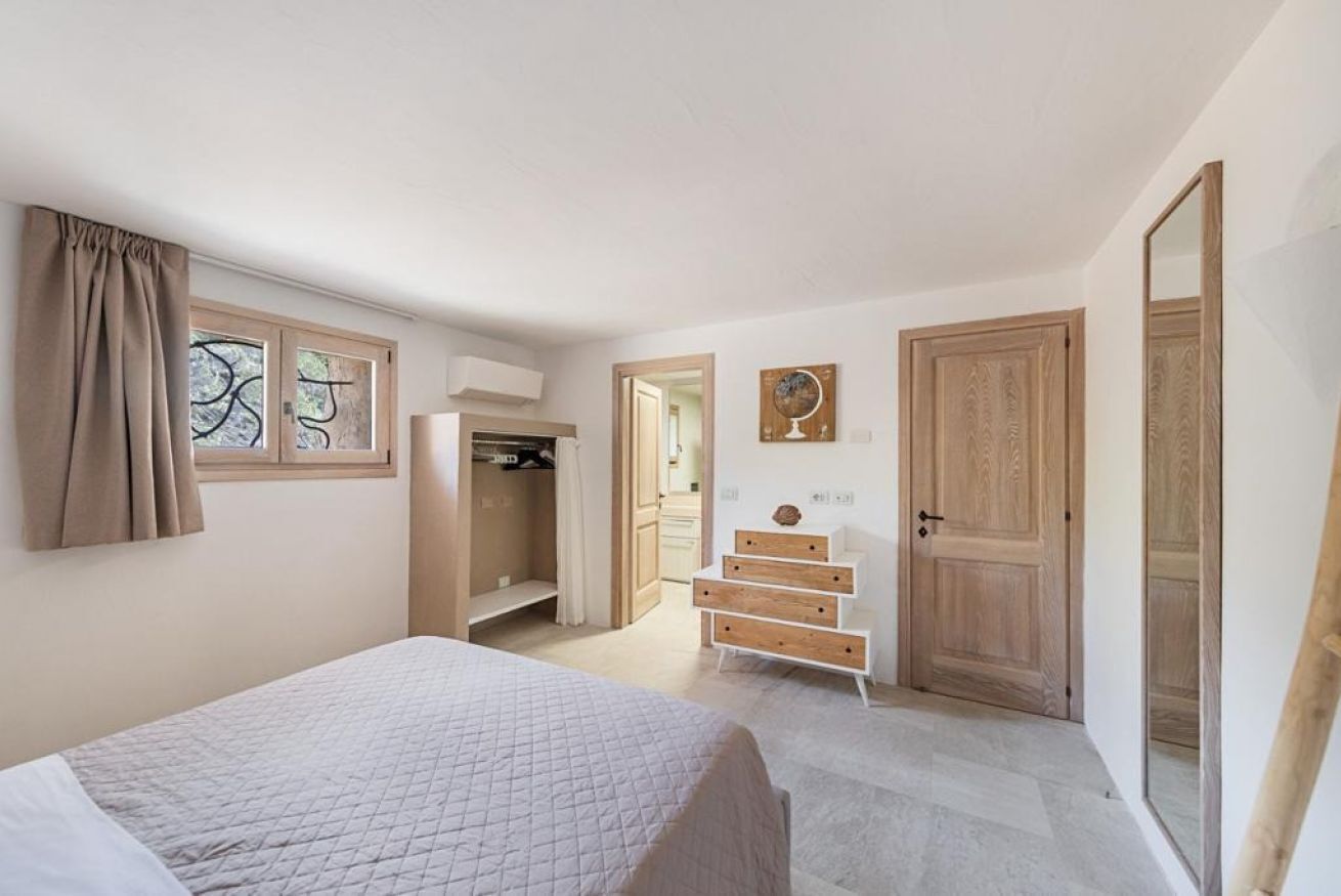 Ein Schlafzimmer mit Bett, Kleiderschrank, Spiegel und einer Tür.