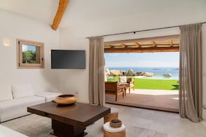 Une chambre moderne avec un canapé, une table basse, un téléviseur et une vue sur une piscine et un paysage.