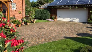 Ein Wohnhaus mit Backsteinfassade, Garage, Solaranlage und befestigter Auffahrt.