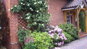 Ein Backsteinhaus mit Garten, einer Holzpergola und einem Pflasterweg.