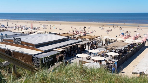 A beachside hotel with outdoor seating, a boardwalk, and a view of the beach and ocean. - Noordzee Apartment 2 (Zandvoort)