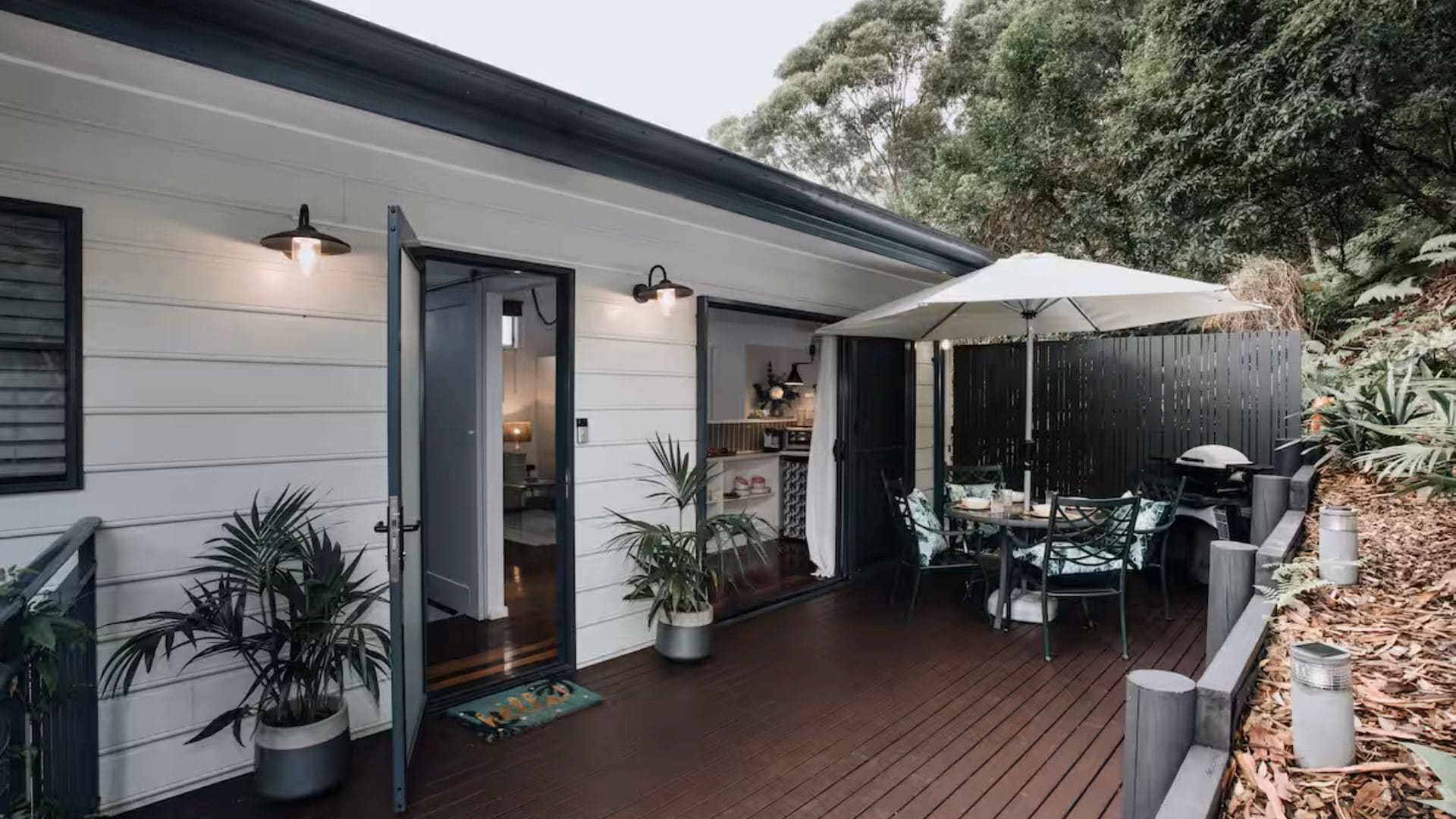 A wooden deck with outdoor furniture, a covered patio, and potted plants.