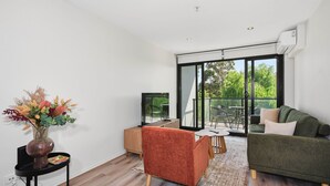 Ein modernes Wohnzimmer mit einer Couch, einem Fernseher, einem Couchtisch und einer Pflanze.